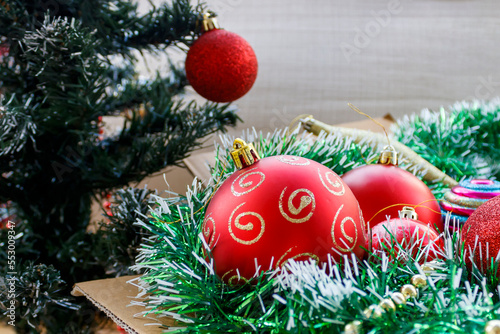 Close-up of balls and tinsel in carton box next to Christmas tree
