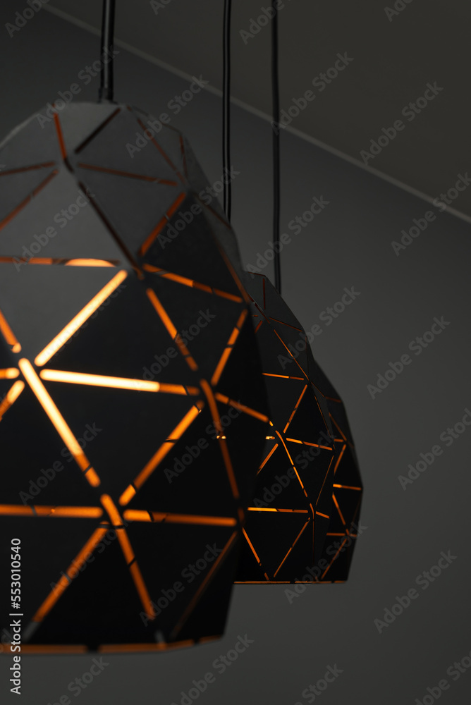Black lamps with a geometric pattern, three lamps on a black background, burning with warm light, with a graphic pattern Black lamps with a geometric pattern, three lamps on a black background, burning with warm light, with a graphic pattern