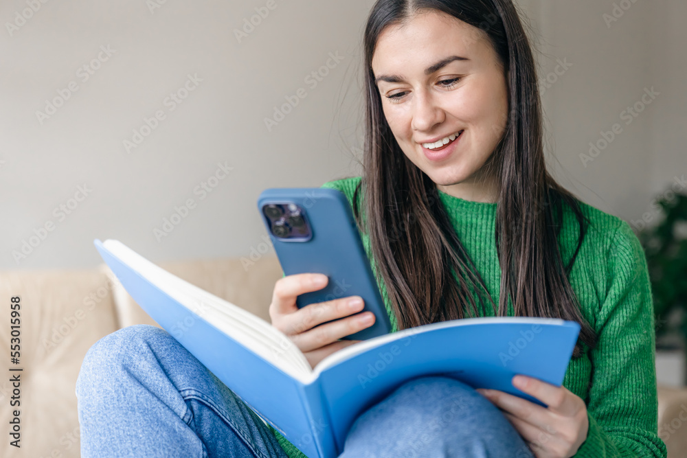 Cheerful young women with a smartphone and a notepad in their hands. Cheerful young women with a smartphone and a notepad in their hands.