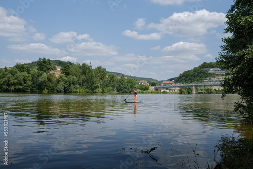 The German river Main with clear water and woman on their stand up paddle board near the town of Zellingen. 