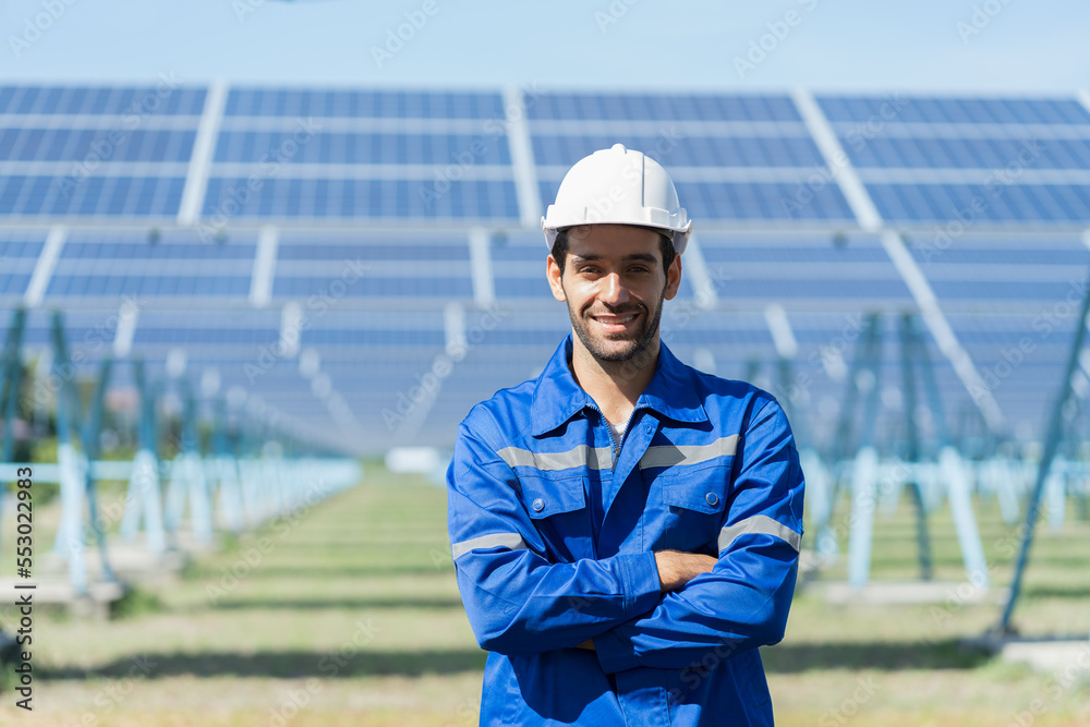 Portrait of smiling male engineers at the solor farm with solar panels blur background. Male electrician worker working by checking operation system at long rows of photovoltaic solar panels farm Portrait of smiling male engineers at the solor farm with solar panels blur background. Male electrician worker working by checking operation system at long rows of photovoltaic solar panels farm