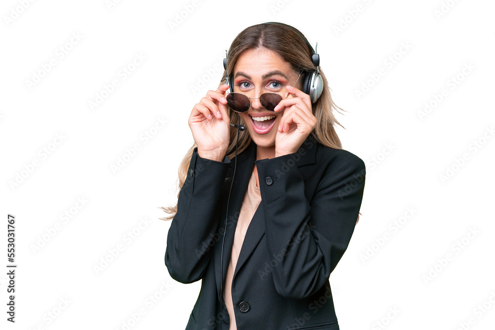 Telemarketer pretty Uruguayan woman working with a headset over isolated background with glasses and surprised Telemarketer pretty Uruguayan woman working with a headset over isolated background with glasses and surprised