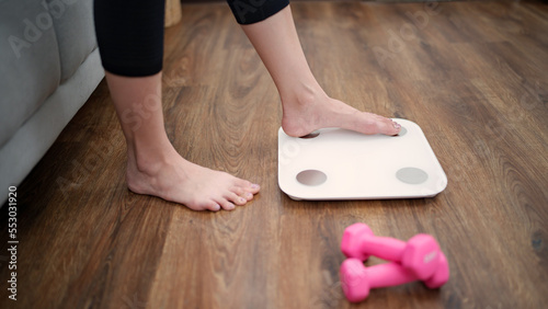 Woman leg stepping on scales at home. Measurement instrument in kilogram for diet Lose weight concept.