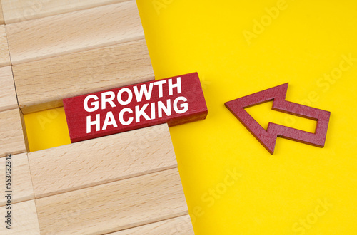 On a yellow surface are wooden blocks and an arrow pointing to a block with the inscription - Growth Hacking photo