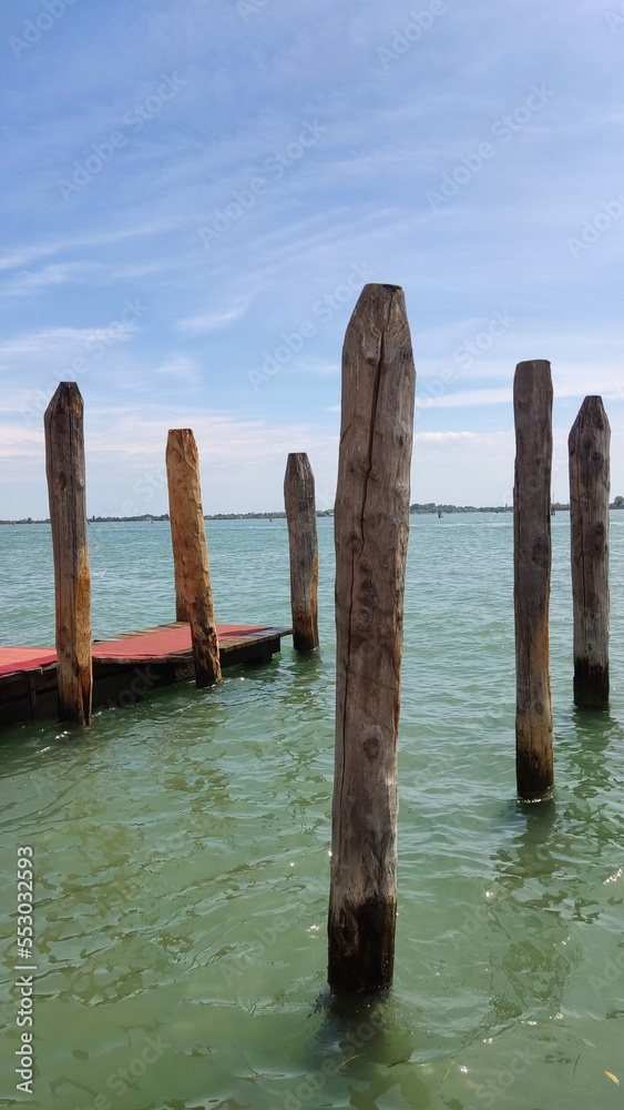 Sea view, wooden bridge and pillars at the sea pier, Venice, Italy