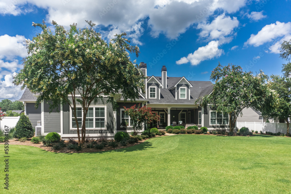 The side view of the backyard of a large gray craftsman new construction house with a landscaped yard The side view of the backyard of a large gray craftsman new construction house with a landscaped yard