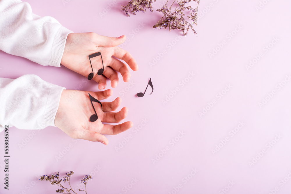 Children's hands hold paper notes on a pink background. Music education. Top view. Children's hands hold paper notes on a pink background. Music education. Top view.