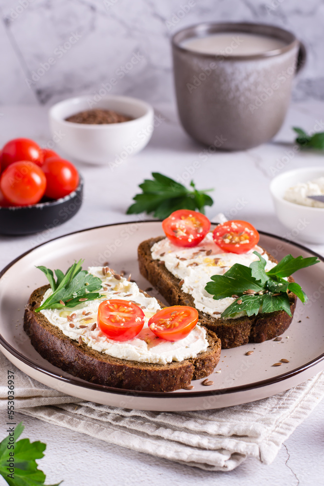 Appetizing bruschetta with ricotta, tomatoes, flax seeds and parsley on a plate. Vertical view