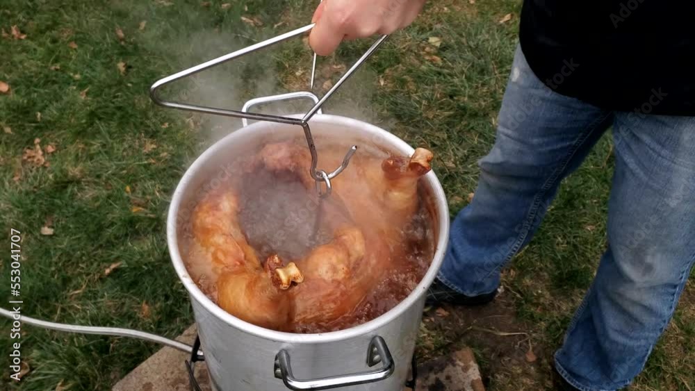 Checking temp and tenderness of large whole Turkey while being deep fried in large pot. 