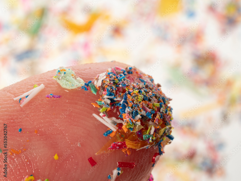 Fototapeta premium Microplastics in water - polluted water - macro photography of finger with microplatics peaces