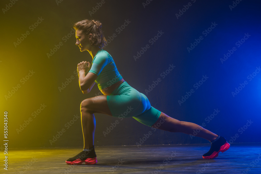 the girl trains on a dark background, modern fitness on a yellow-blue background with a place for text the girl trains on a dark background, modern fitness on a yellow-blue background with a place for text