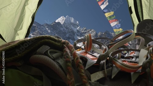 Travel in Nepal Himalayas mountains. Ready for mountain climbing. Camera moves inside tent where the sleeping bag, backpack, crampon, boots. Buddhist flags fluttering in the wind. Sleeping in the tent