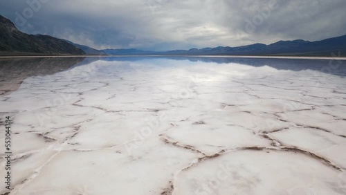 Walking in mirror surface of salt crust formations with water in Badwater Basin, Death Valley National Park. California, USA