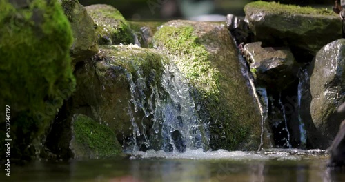 Slow motion of small waterfall stream at a water pond in the forest