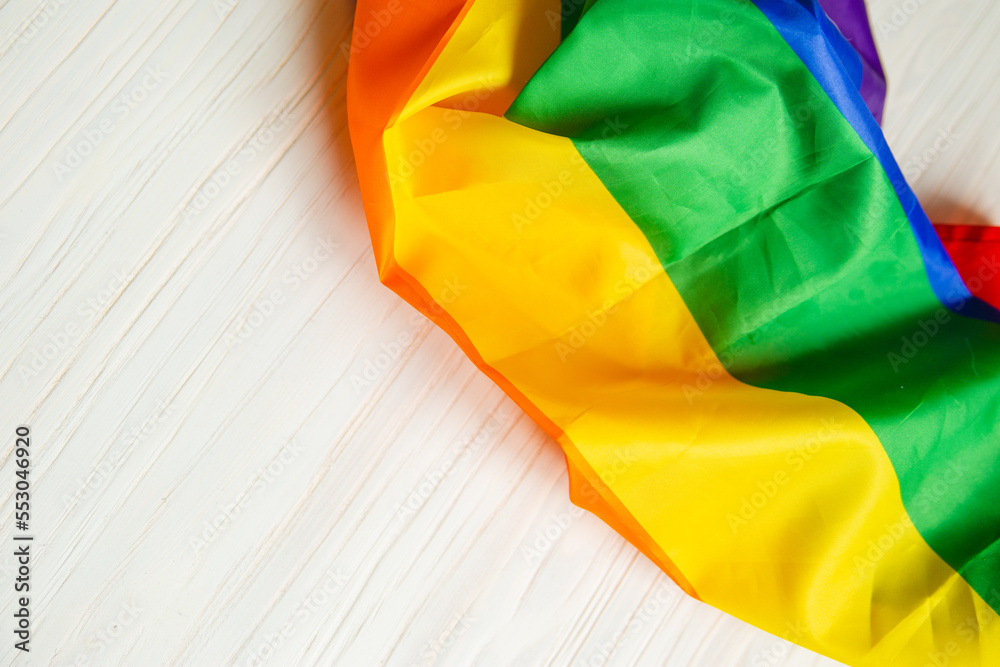 Rainbow LGBT flag on a white wooden background. View from above. Wood texture . Place for text.