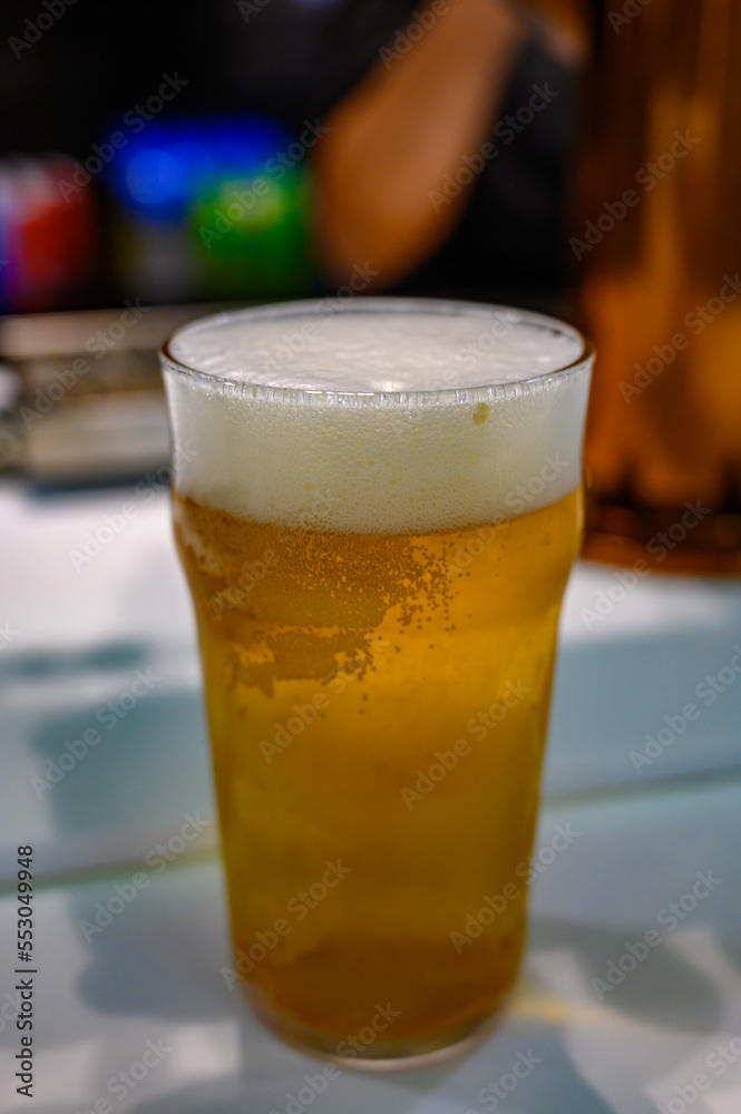 Fresh draught lager or IPA beer is glass served in indoor cafe close up, pint of beer Fresh draught lager or IPA beer is glass served in indoor cafe close up, pint of beer