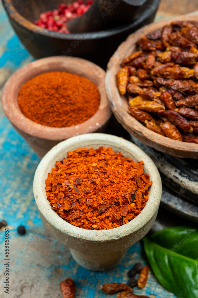 Colorful ground spicy chili peppers , pimento and curcuma is clay pots close up