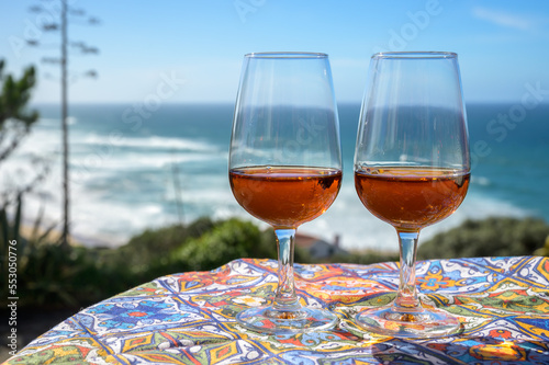 Tasting of sweet moscatel de setubal or porto portuguese wine and view on blue Atlantic ocean near Sintra in Lisbon area, Portugal photo