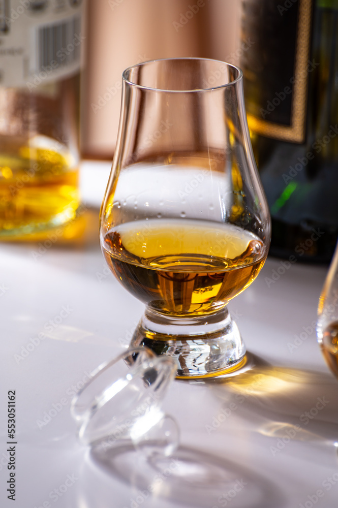 Tasting of whiskey, tulip-shaped tasting glasses with dram of Scotch single malt or blended whisky on white table Tasting of whiskey, tulip-shaped tasting glasses with dram of Scotch single malt or blended whisky on white table
