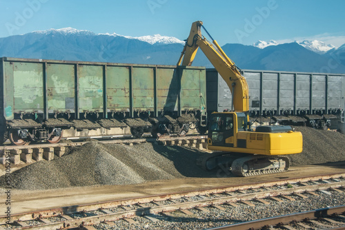 Unloading unloading rubble with an excavator wagons with bulk cargo gravel, sand at the station.