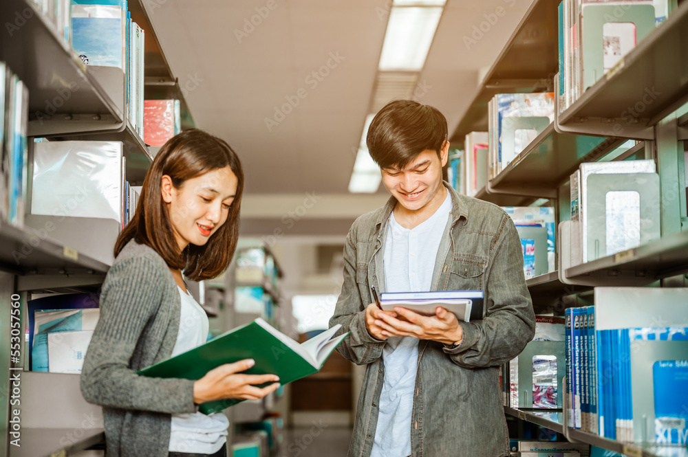 Male and female students standing reading books for exams in the university library. Education,school,library and knowledge concepts. Male and female students standing reading books for exams in the university library. Education,school,library and knowledge concepts.