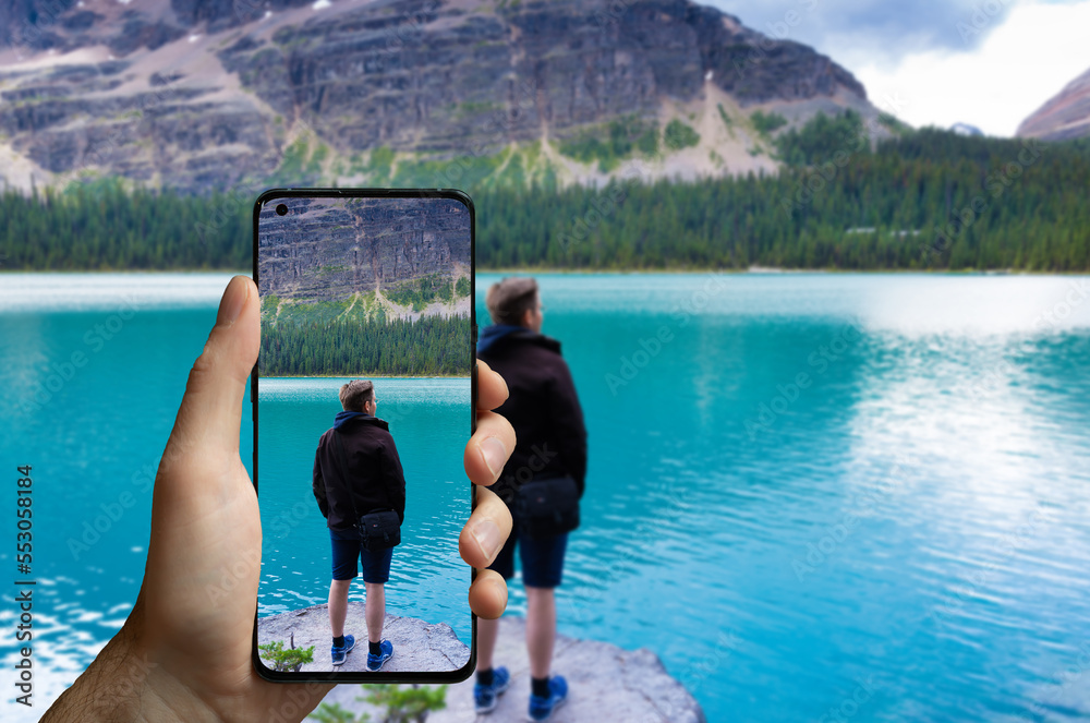 Φωτογραφία Tourist taking a picture with a mobile phone of a man standing at the lake Ohara, Canada