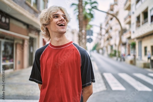 Young blond man smiling confident looking to the side at street