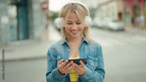 Young blonde woman smiling confident watching video on smartphone at street