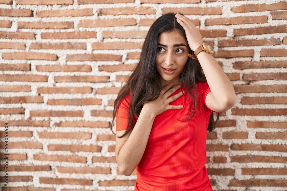 Young teenager girl standing over bricks wall touching forehead for illness and fever, flu and cold, virus sick Young teenager girl standing over bricks wall touching forehead for illness and fever, flu and cold, virus sick