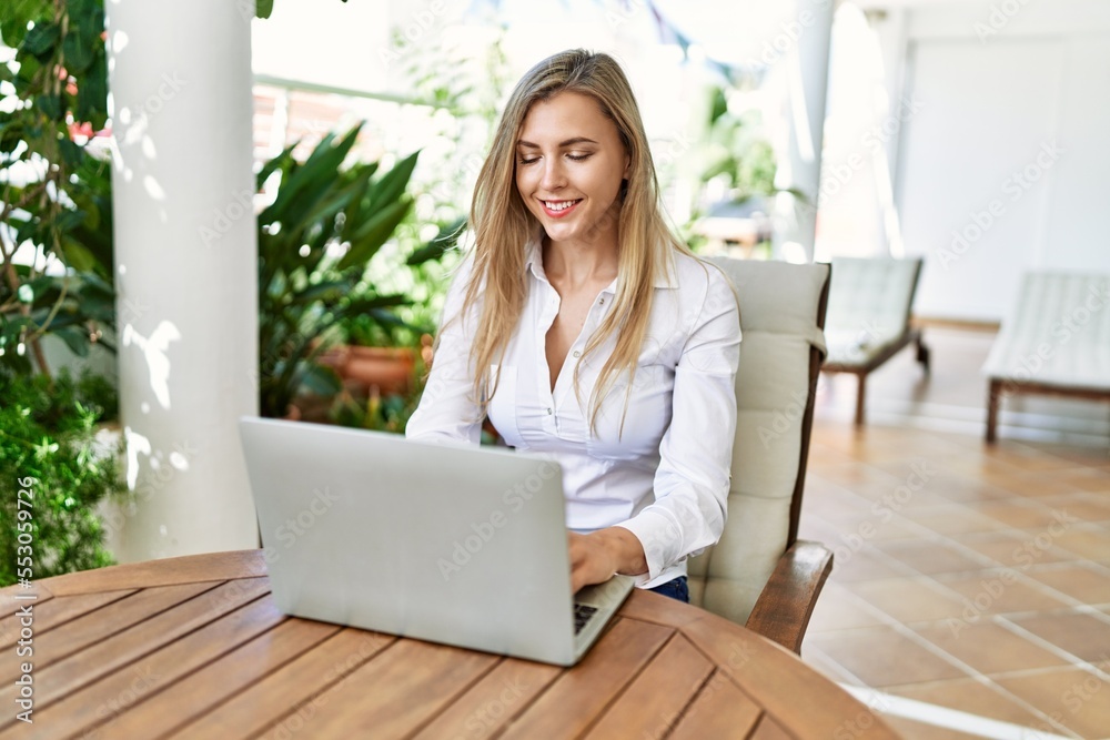 Young blonde woman smiling happy using laptop working at the terrace. Young blonde woman smiling happy using laptop working at the terrace.