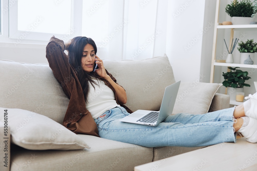 Woman blogger with phone lying at home and talking on the phone on sofa with laptop and working freelancer online, selfie Woman blogger with phone lying at home and talking on the phone on sofa with laptop and working freelancer online, selfie