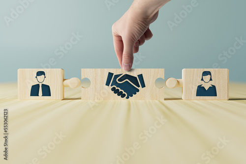 Fotografia The hand holds wooden wooden blocks with icons of a woman and a man and shaking hands in the act of consent