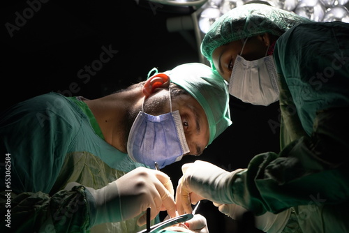 Doctor performing nose surgery in the operating room. green dresses and black room in the operating room 