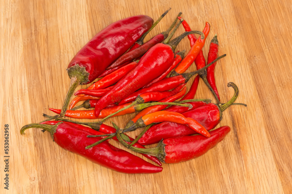 Two varieties of dried red pepper chili on wooden surface