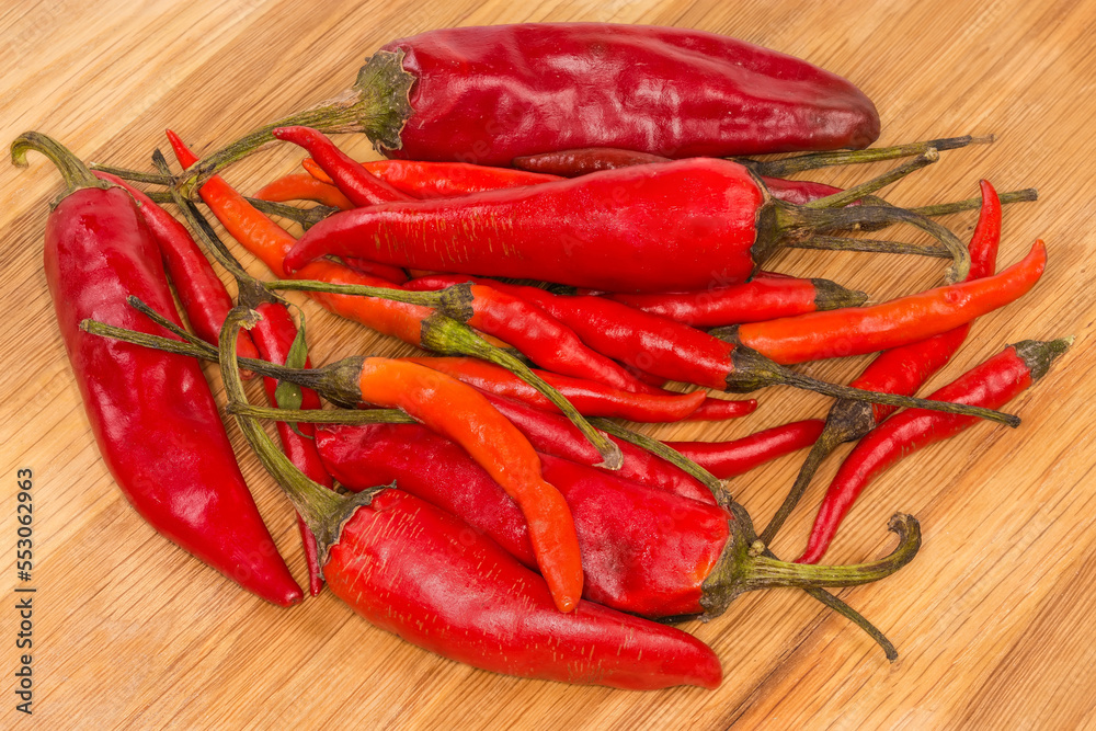 Small and big varieties of pepper chili on wooden surface