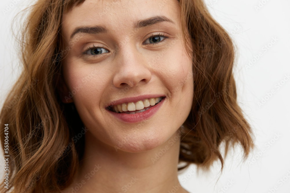 a close, horizontal portrait of a joyful, happy woman in a yellow T-shirt on a light background smiling broadly and looking at the camera a close, horizontal portrait of a joyful, happy woman in a yellow T-shirt on a light background smiling broadly and looking at the camera