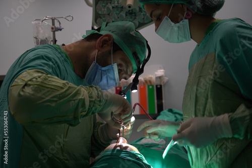 Doctor performing nose surgery in the operating room. green dresses and black room in the operating room 