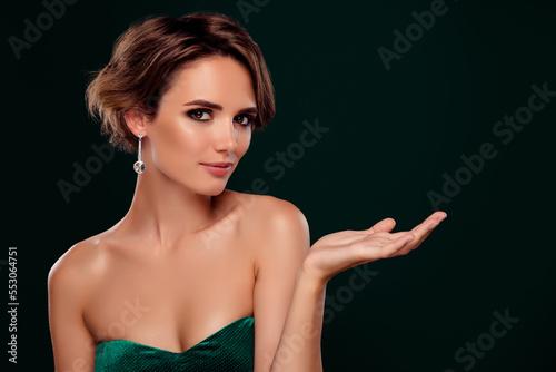 Adorable hollywood star presenting empty space promoting best cosmetics isolated on green color background photo