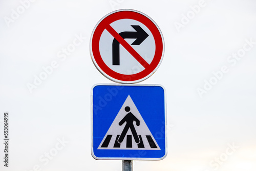 Blue and white pedestrian crossing sign on the sky background with prohibited from turning right. © Steam visuals