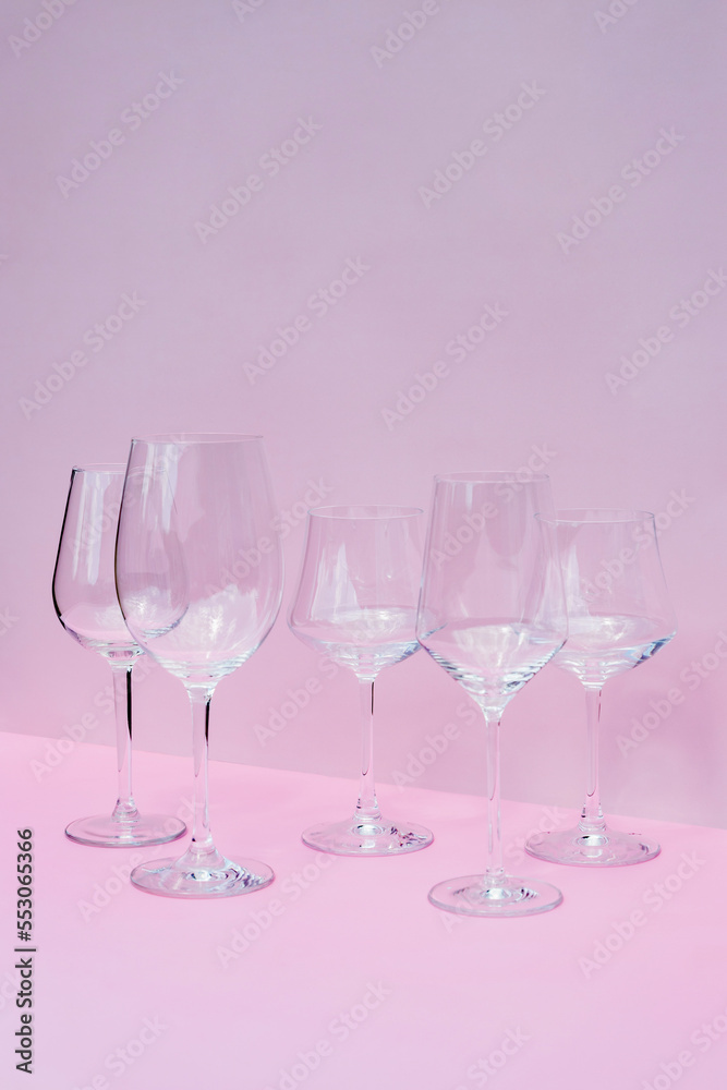 Various empty wine glasses on a pink background with space for text.