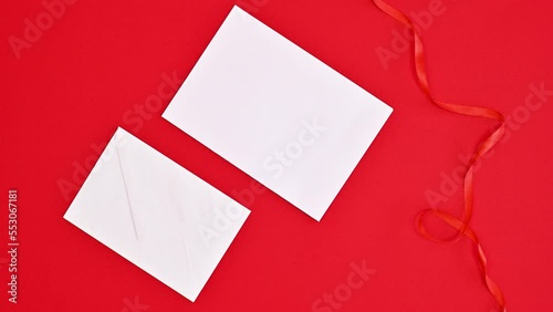 Opening gift envelope with copy space paper card for text on red background. Christmas stop motion. Flat lay