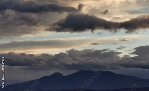 Nuvole nere e cielo azzurro sopra le montagne © GjGj