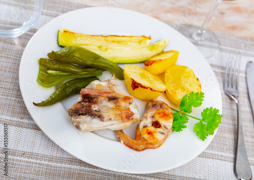 Portion of just cooked rabbit with vegetables. Rabbit meat garnished with potato, zucchini and bell pepper.