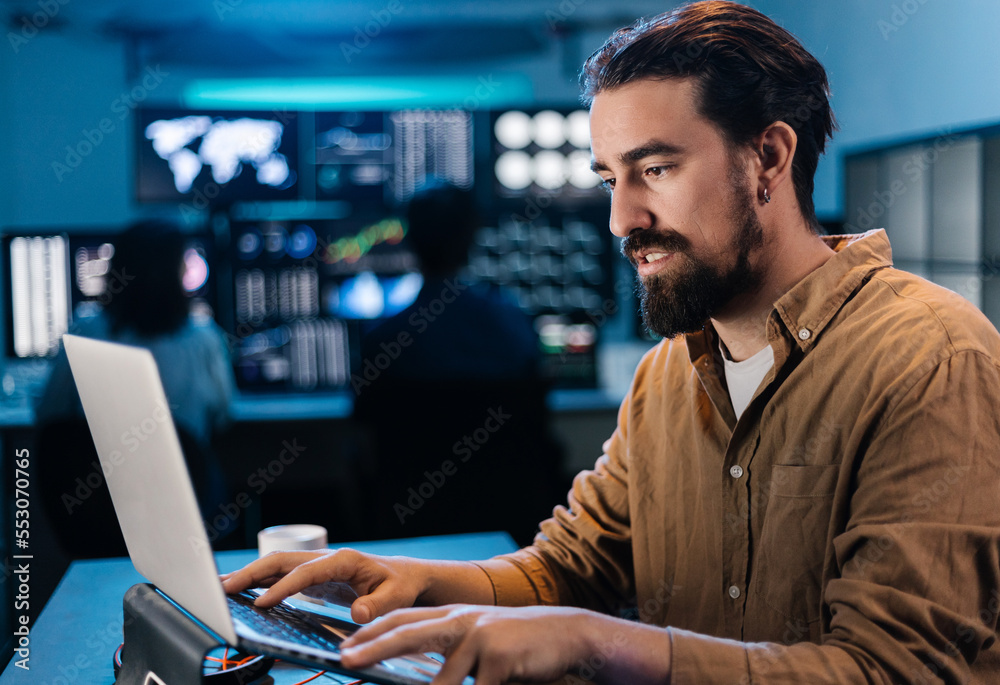 Young trader businessman working on laptop in dark office. Stock market exchange concept Young trader businessman working on laptop in dark office. Stock market exchange concept