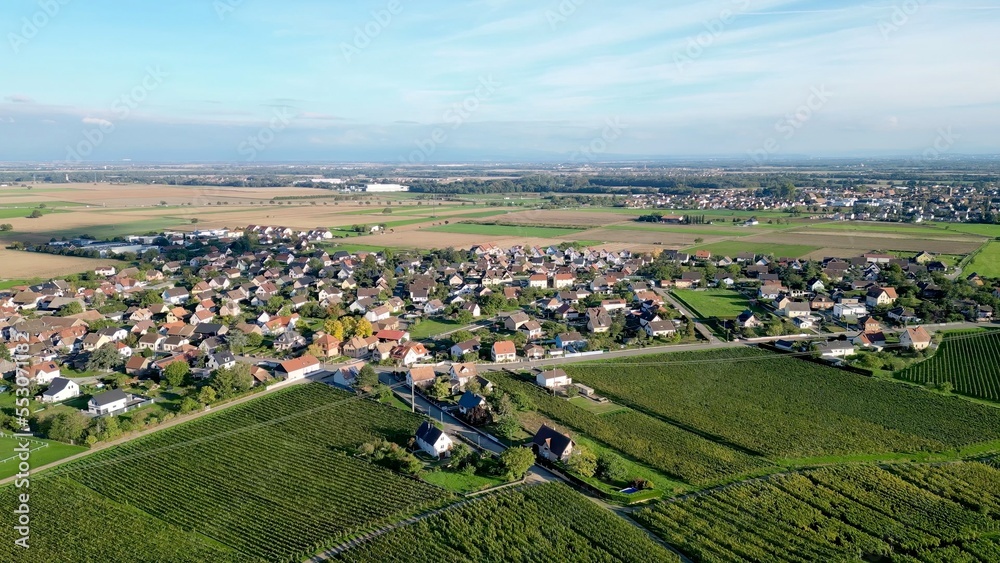 Panoramic aerial drone top view of the rural village of Bergholtz (Upper-Rhine, France) in summer day, between mountains, vineyards and fields of the Alsace plain