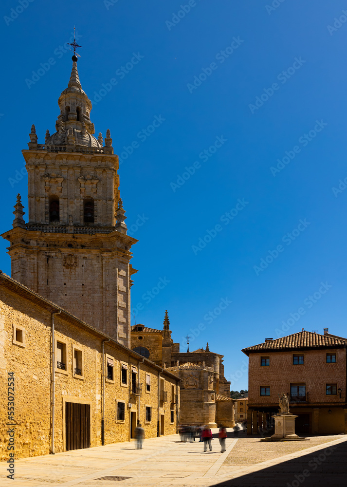 View of street in historical area of El Burgo de Osma overlooking Gothic bell tower medieval Roman Catholic Cathedral of Assumption with pointed spire and dome with figured turrets on sunny day, Spain