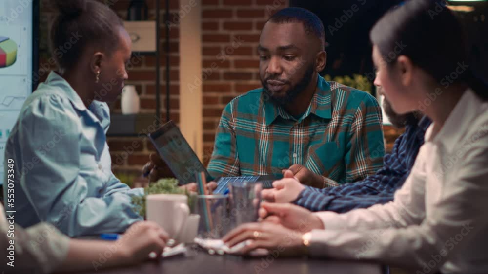 Business meeting, african american analytics specialist showing company revenue report data on laptop screen. Coworkers discussing statistics presentation, employees listening to analyst speaking Business meeting, african american analytics specialist showing company revenue report data on laptop screen. Coworkers discussing statistics presentation, employees listening to analyst speaking