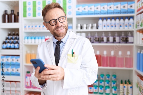 Middle age man pharmacist using smartphone working at pharmacy © Krakenimages.com