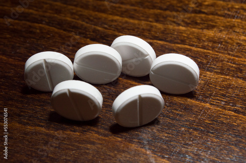 White round tablets on a wooden surface. A medicinal product.