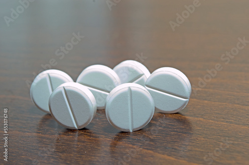 White round tablets on a wooden surface. A medicinal product.